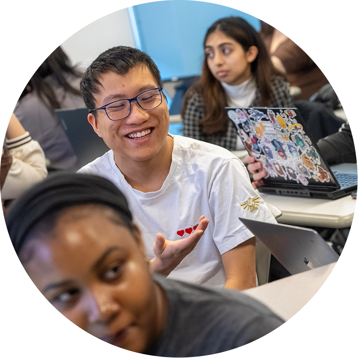 College of Business Students in class with the focus being on one student who is smiling in his conversation with other students