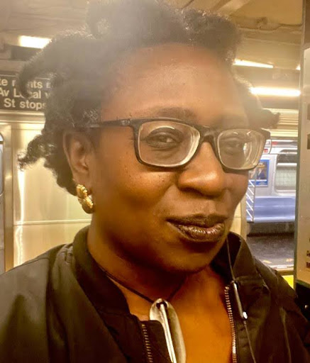 Person with glasses smiling inside a subway station.