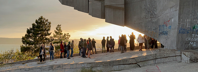 A group of people standing together on a concrete wall, smiling and enjoying the outdoors.