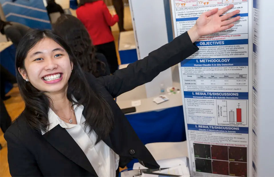 Natasha proudly gestures to her poster presentation