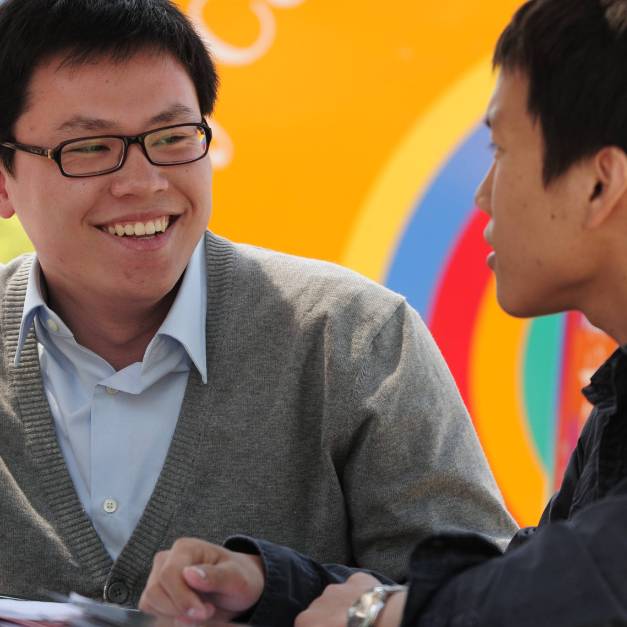 Two students smiling and chatting in front of a colorful mural