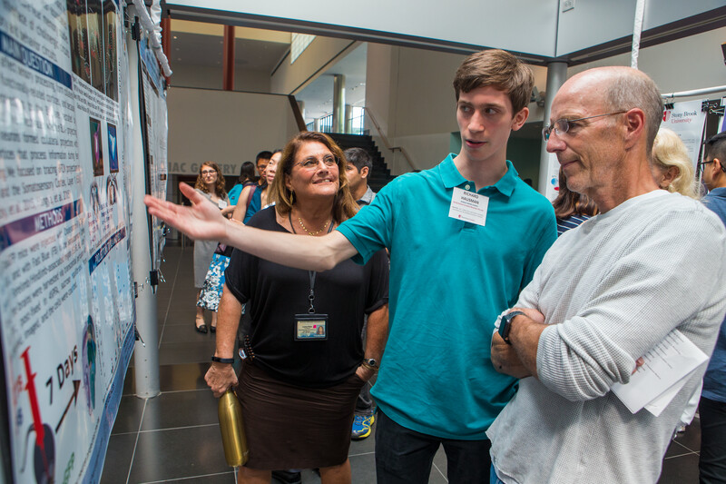 teenage boy in blue shirt presenting science poster